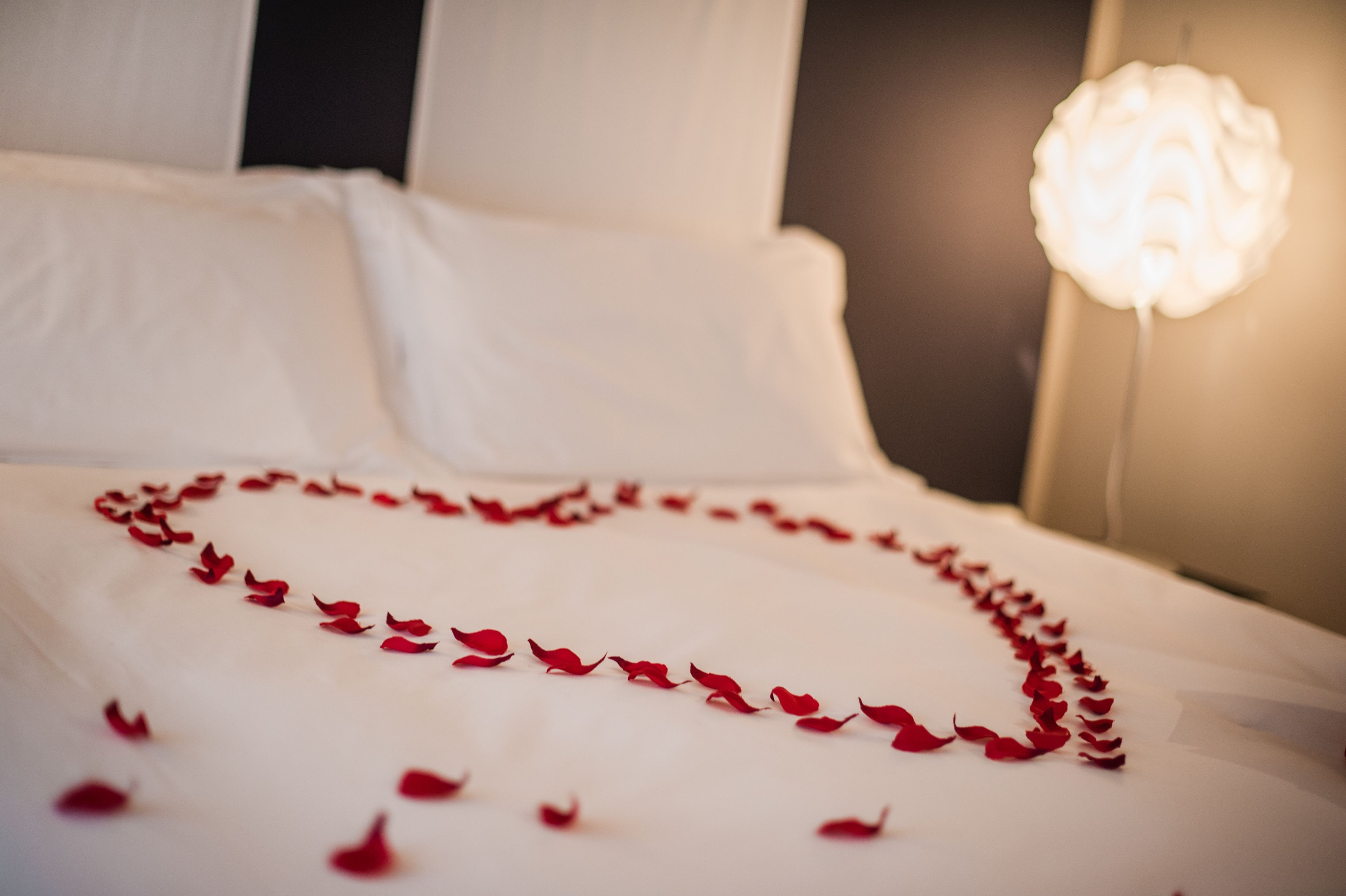 Un lit décoré de pétales de roses rouges disposés en forme de cœur.