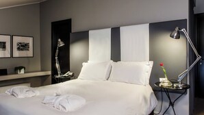 A neatly made bed with white linens and two pillows, a bedside table with a lamp and a vase with a single red rose, and two framed pictures on the wall. - Hotel Casa Poli (Mantua)