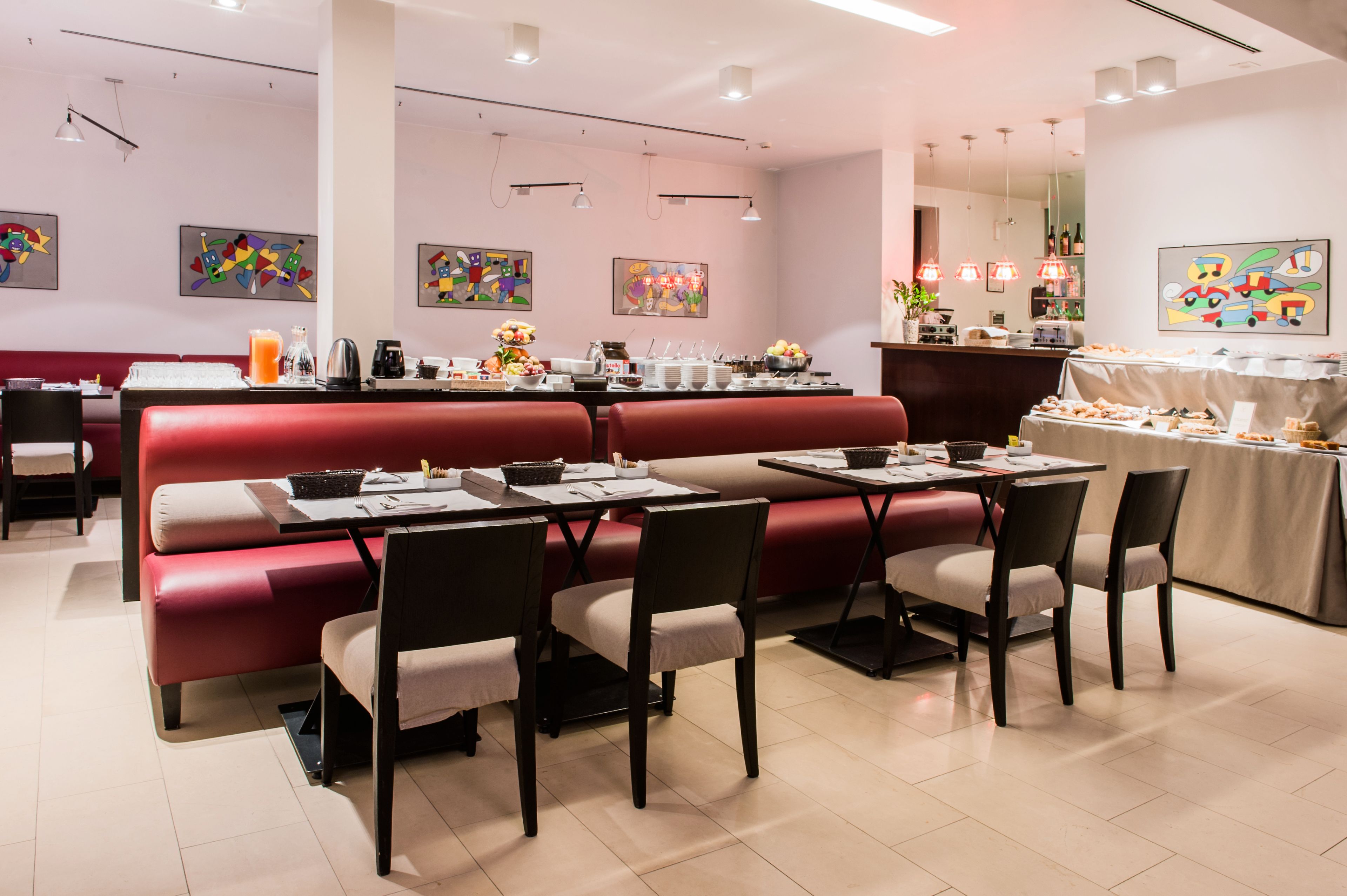 A restaurant with red booths, tables, and chairs, with artwork on the walls and a buffet area.