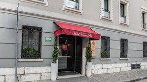 A hotel entrance with a red awning, a sign indicating it is a hotel, and potted plants on either side. - Hotel Casa Poli (Mantua)