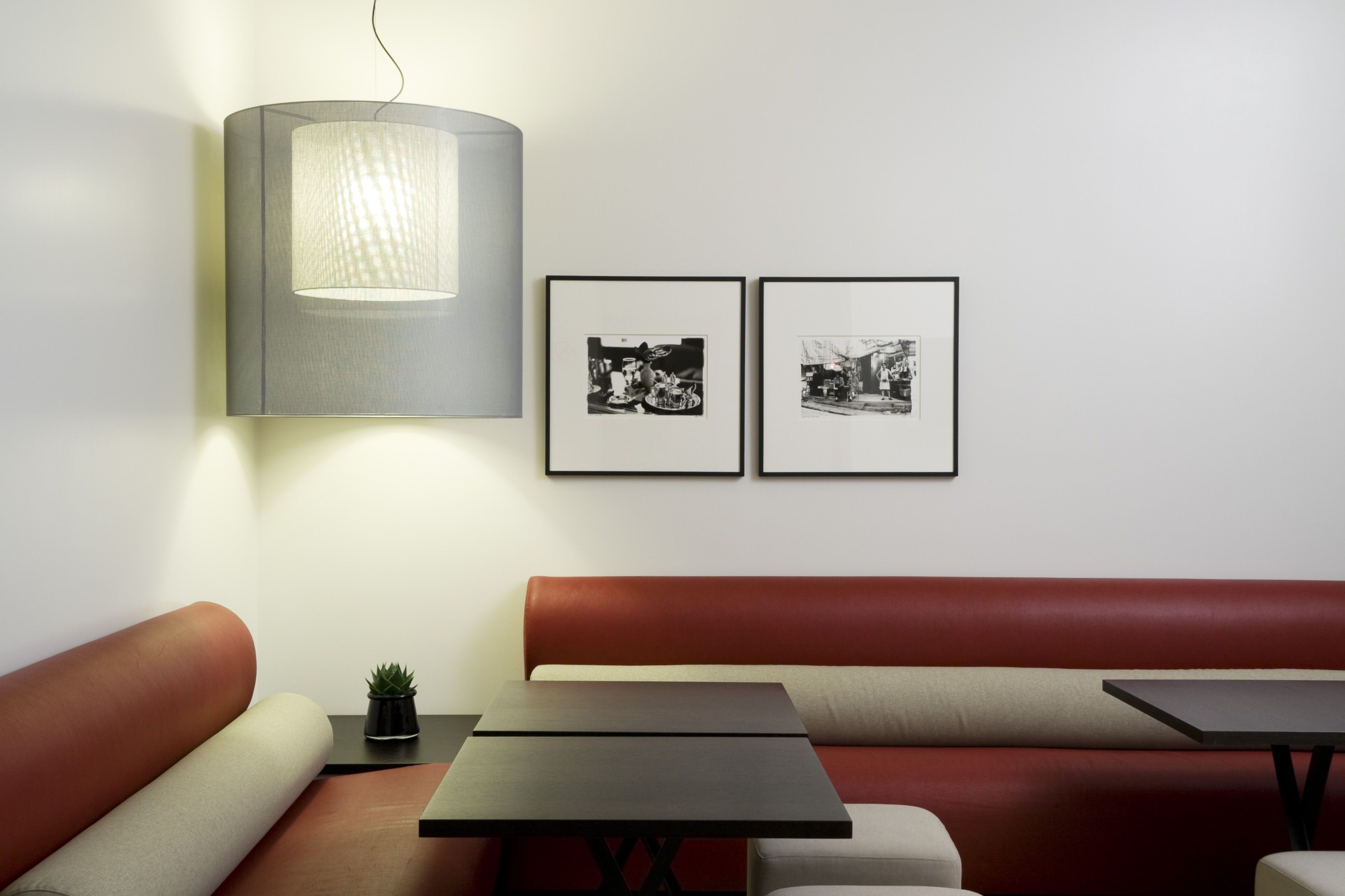 A modern interior with a sofa, two tables, a lamp, and two framed photographs on the wall.