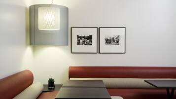 A modern interior with a sofa, two tables, a lamp, and two framed photographs on the wall.
