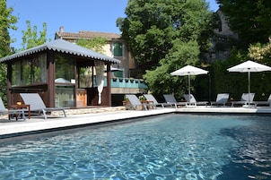 Une piscine équipée de chaises longues et de parasols, un kiosque et un bâtiment doté d’un balcon donnant sur la piscine.