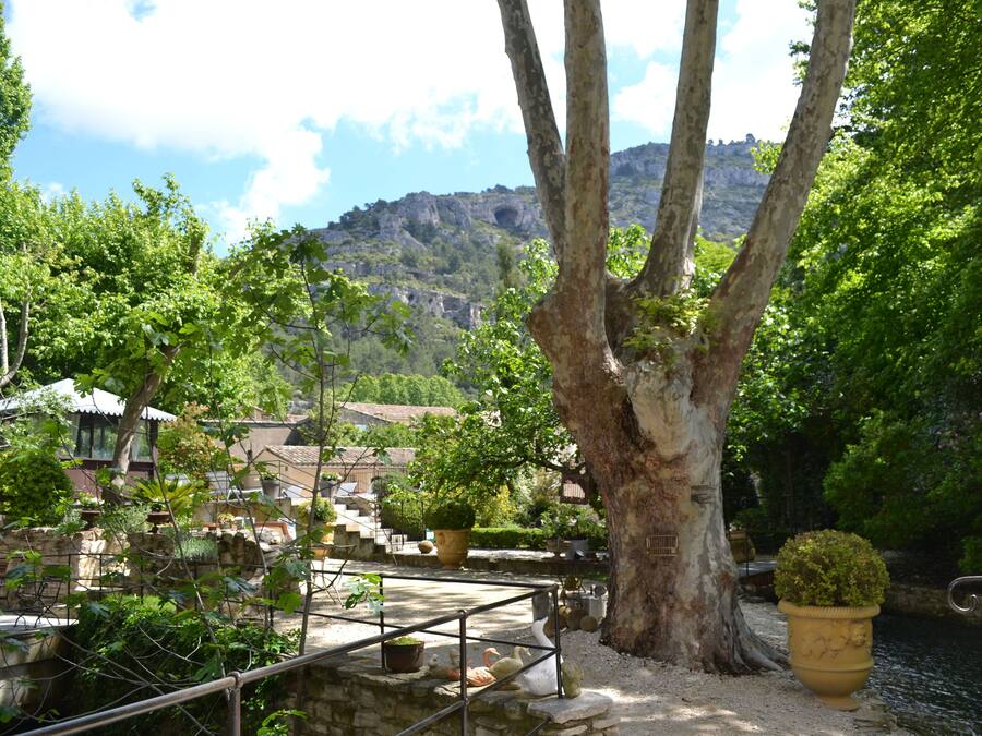 A courtyard with stone benches, potted plants, and a view of a hillside.