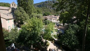 A courtyard with outdoor seating, surrounded by trees and buildings, including a church with a bell tower.