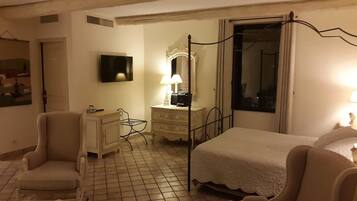 Una habitación de hotel con una cama, una silla, un tocador, un espejo y una ventana.
