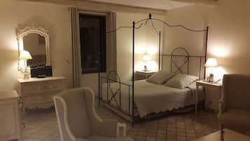 Un lit à baldaquin, deux tables de chevet avec des lampes, une chaise, une commode et un miroir.