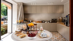 A kitchen with a breakfast buffet setup, including fruits, pastries, and beverages.