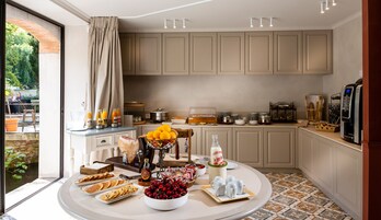 Une cuisine aménagée pour un buffet de petit-déjeuner, comprenant des fruits, des viennoiseries et des boissons.