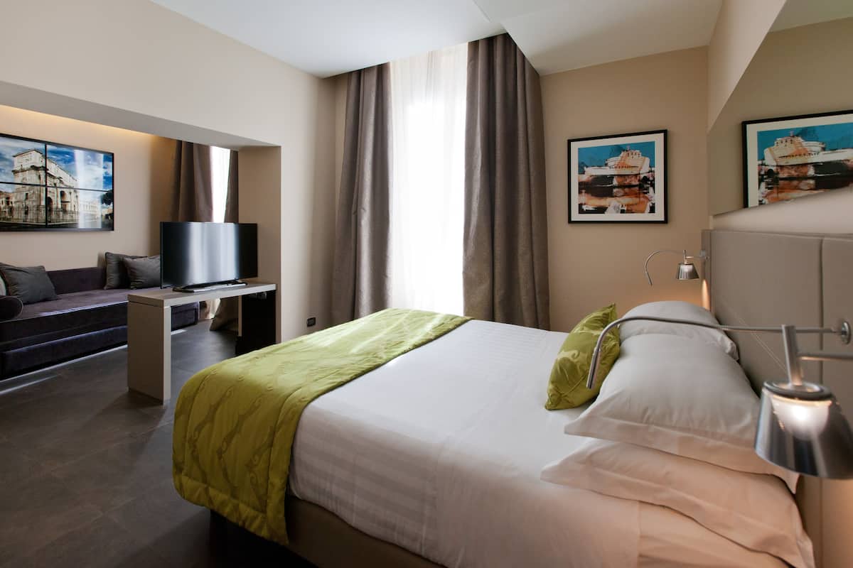 Une chambre d’hôtel avec un lit, un bureau, une télévision et des œuvres d’art accrochées aux murs.