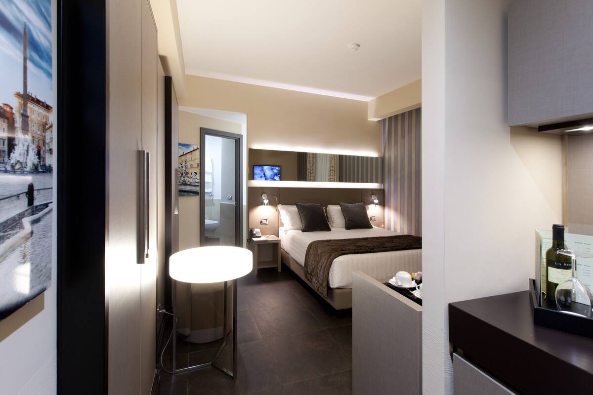Une chambre d’hôtel moderne équipée d’un lit, de tables de chevet, d’une télévision et d’un mini-bar.