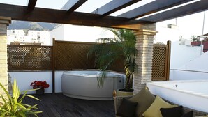 Terraza en la azotea con hidromasaje, zona de estar y plantas en macetas.