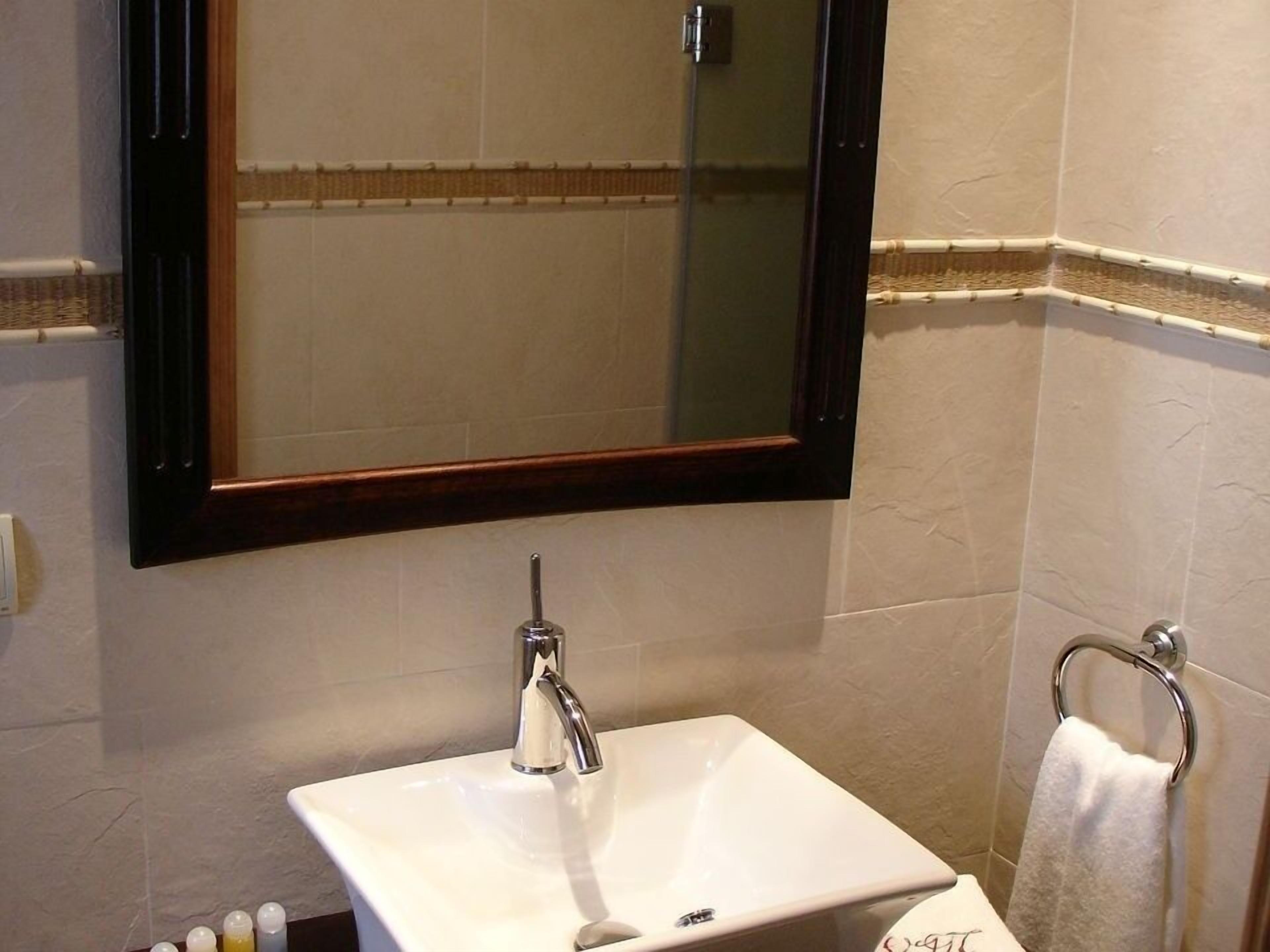 A bathroom with a white sink, a mirror with a wooden frame, and a towel rack.