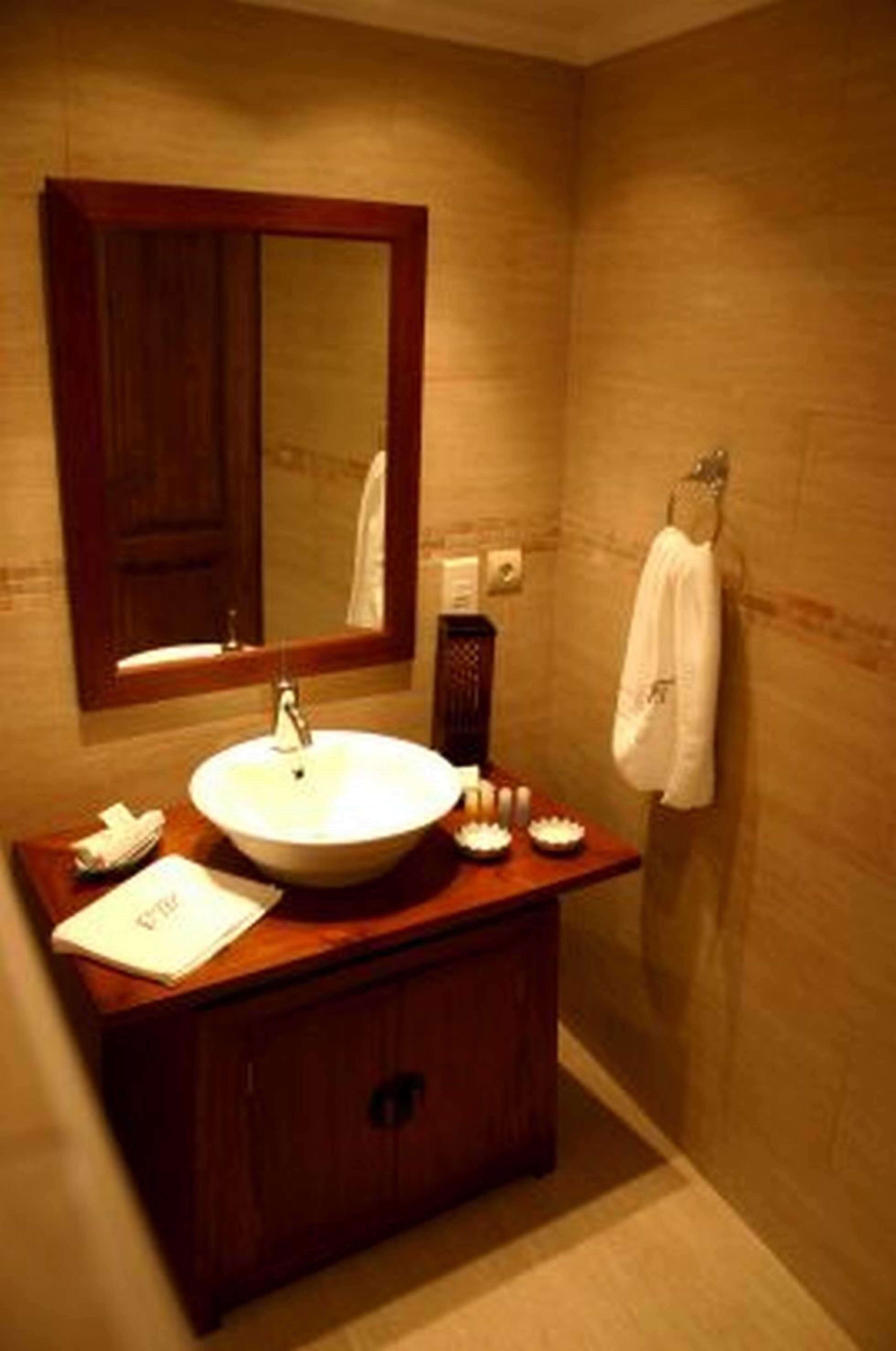 A bathroom with a wooden vanity, a large mirror, and a towel hanging on the wall.