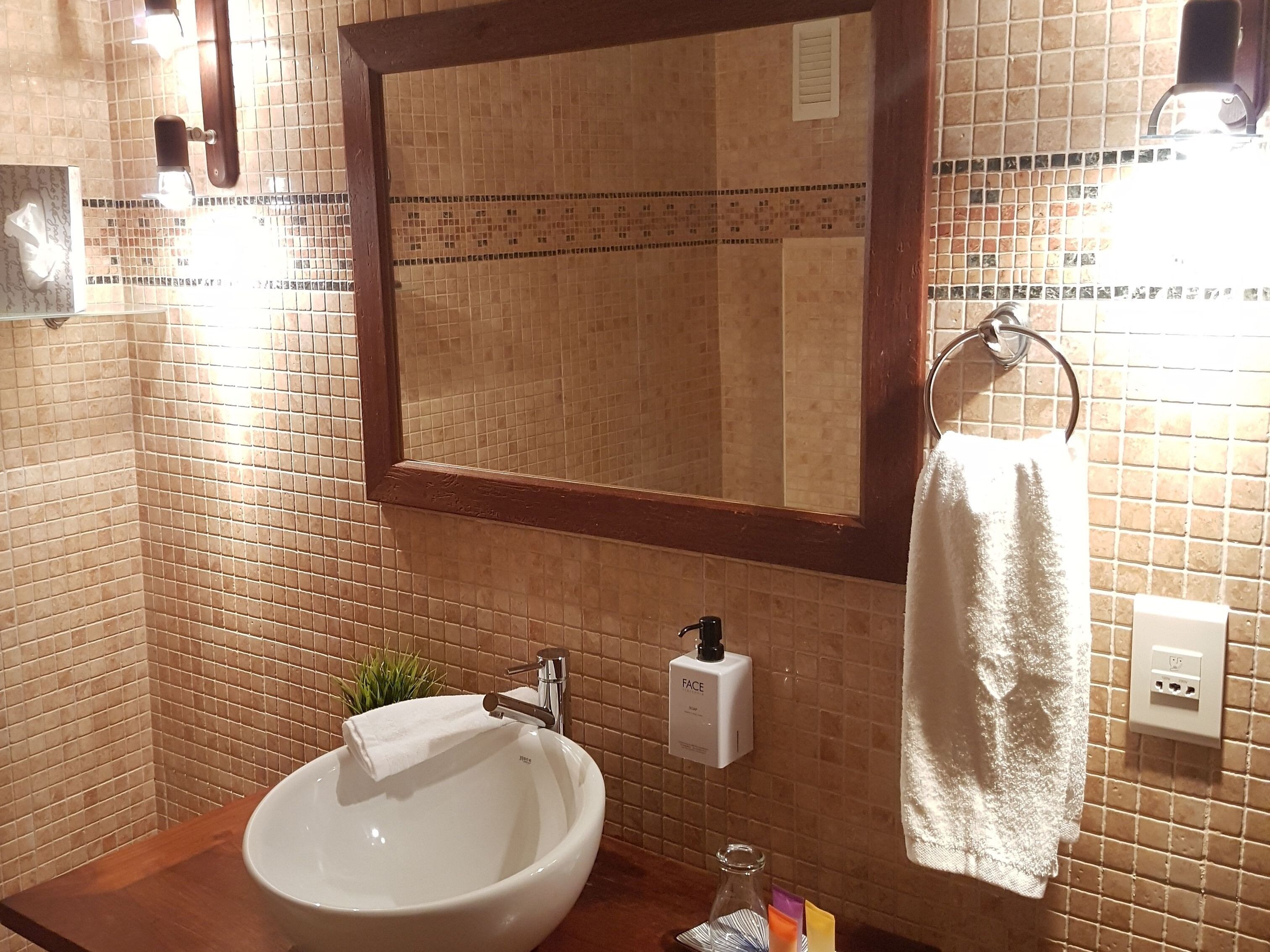Een badkamer met een grote spiegel, een wastafel en een handdoekhouder.