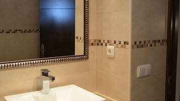 A bathroom with a white sink, a large mirror, and tiled walls.