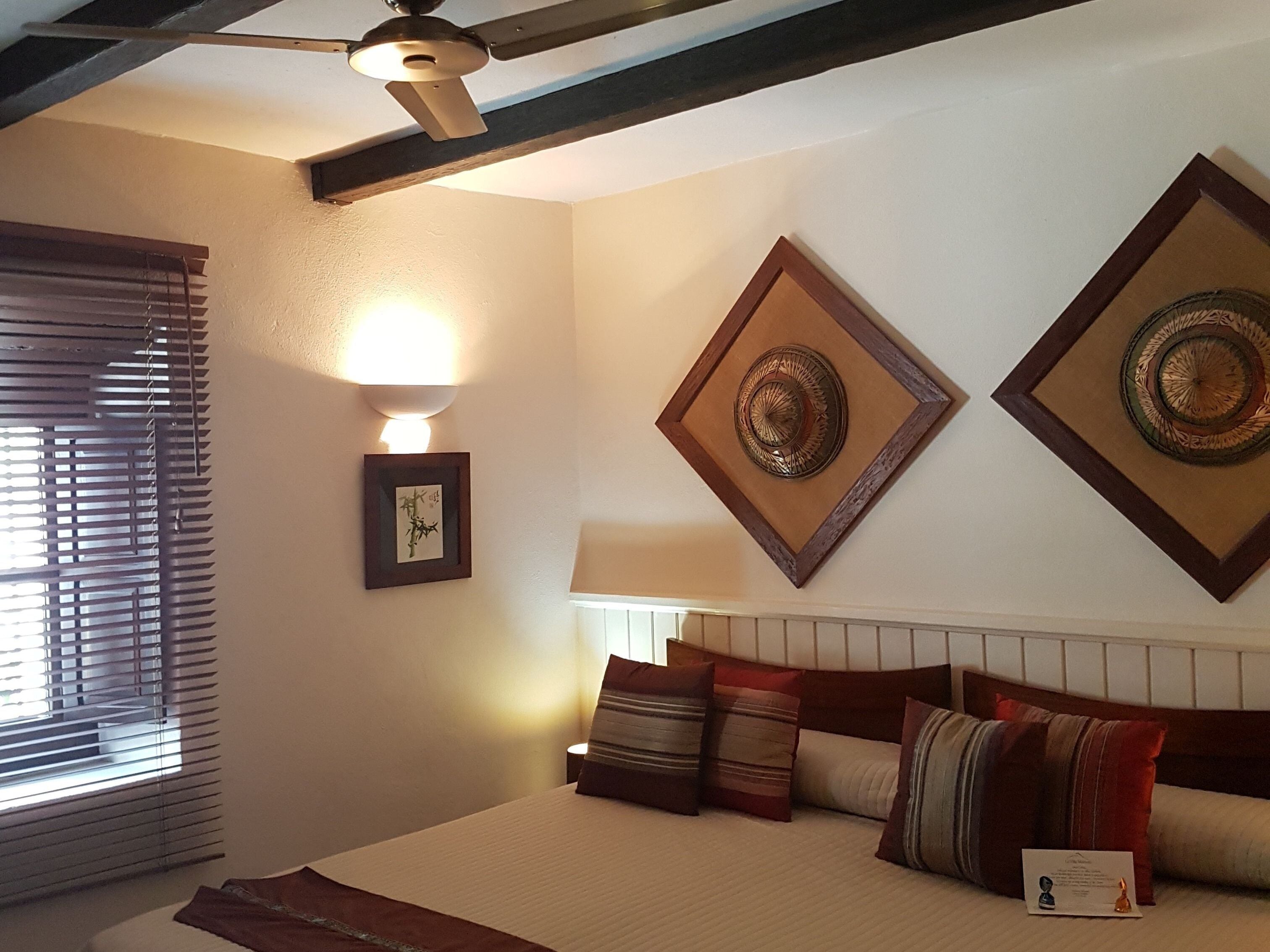 Ein Schlafzimmer mit Bett, Kissen, Nachttisch, Wandlampe und Wanddekoration.