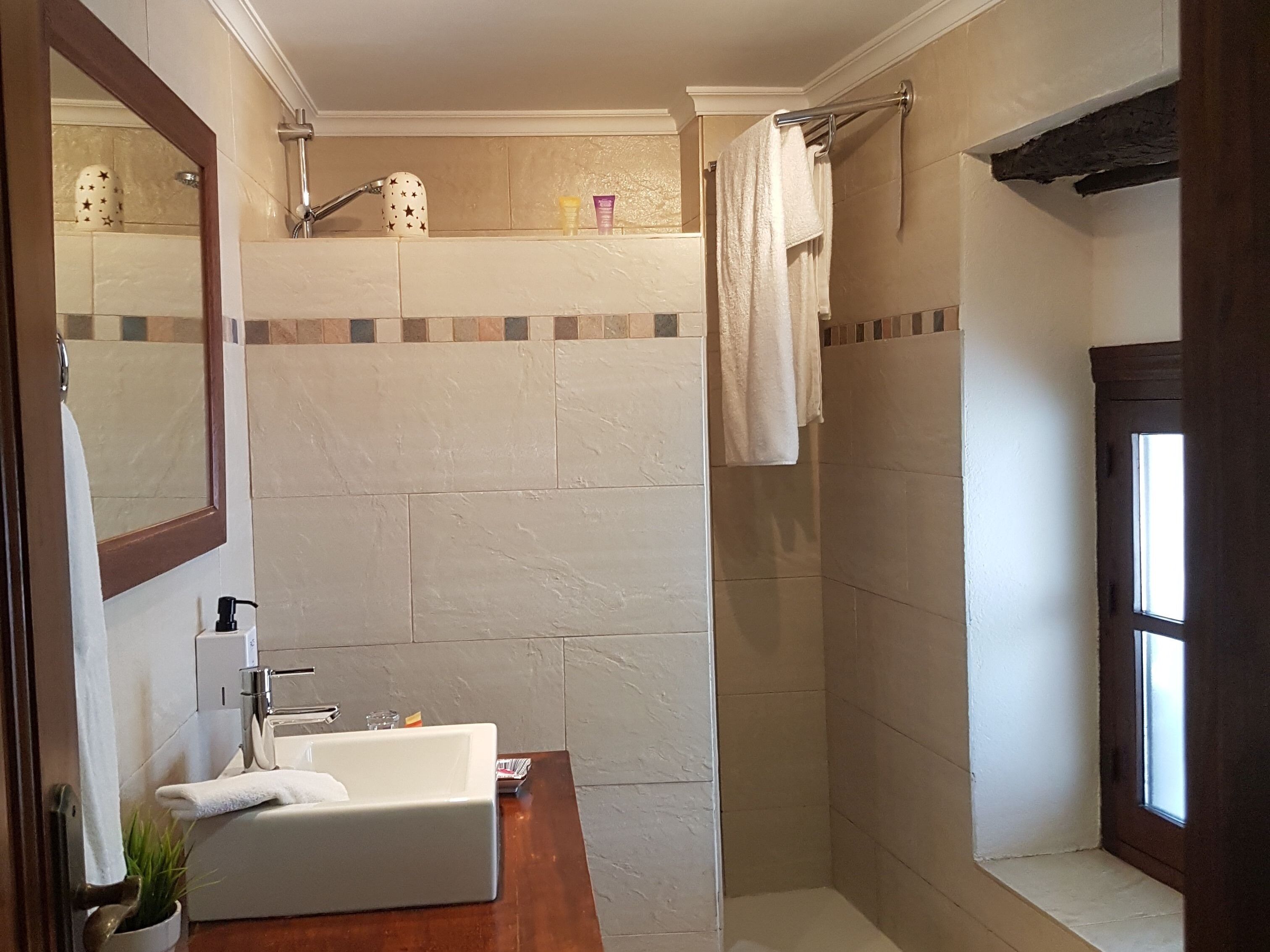 Een badkamer met een wit wastafelmeubel, spiegel en douche.