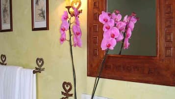 Un baño con puerta de madera, un espejo y una lámpara en la pared.