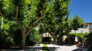 A courtyard with a gravel path, outdoor seating, and a bicycle. - Hotel Restaurant La Ferme (Avignon)