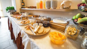 Una mesa de buffet con diversos alimentos para el desayuno, como pasteles, frutas y bebidas.