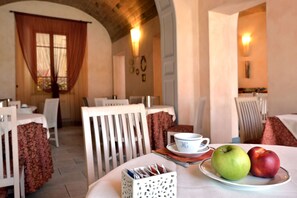 A dining area with tables, chairs, a tray with apples, and a cup. - Hotel La Colonna (Siena)