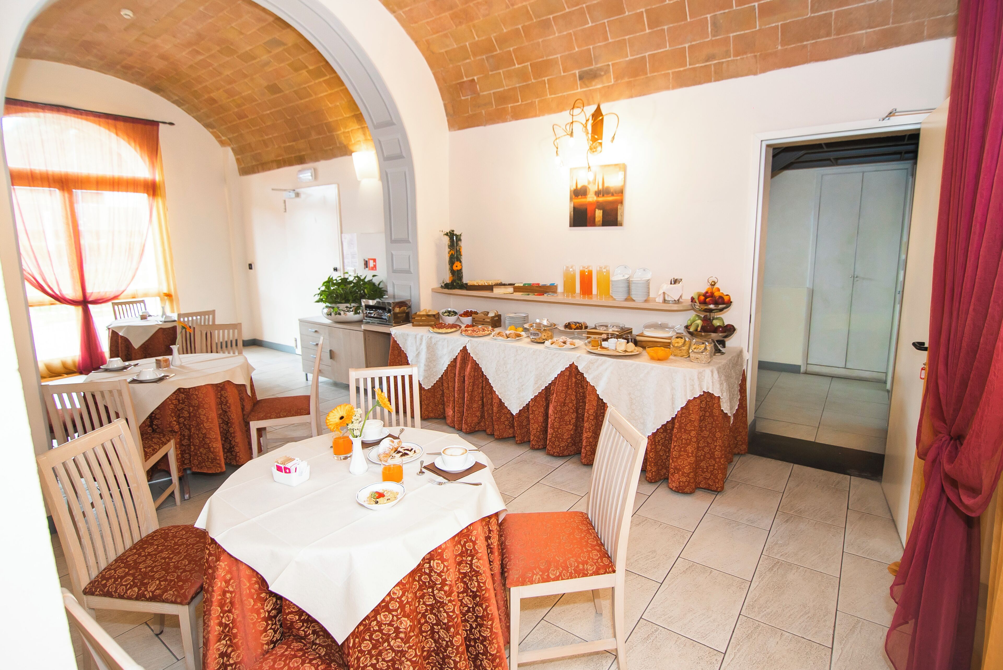 A dining area with round tables, chairs, and a buffet setup.