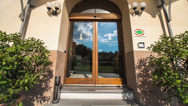 Entrada de hotel con puertas dobles, dos lámparas fijadas a la pared y un cartel que indica que no se permite fumar.