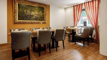 A dining area with a large painting on the wall, a wooden table, and grey upholstered chairs.