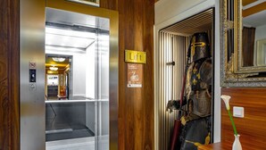An elevator interior with a 'Lift' sign, a wooden panel wall, and a suit of armor on display. - Hotel Burgschmiet (Nuremberg)