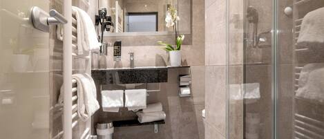 A modern bathroom with a glass shower enclosure, a vanity with a mirror, and a towel rack.