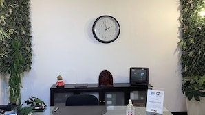 A conference room with a glass table, black chairs, a clock on the wall, and greenery on the sides. - CostantiNapoli 27 (Naples)