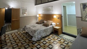 A bedroom with a bed, nightstands, a mirror, and a patterned floor. - CostantiNapoli 27 (Naples)