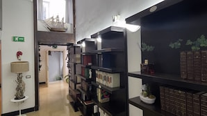 A library with bookshelves, a lamp, and a ship model on the wall. - CostantiNapoli 27 (Naples)