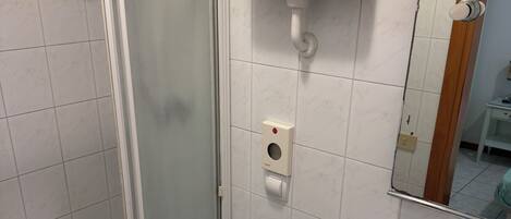 Un baño con ducha de mampara de vidrio, inodoro y lavamanos.