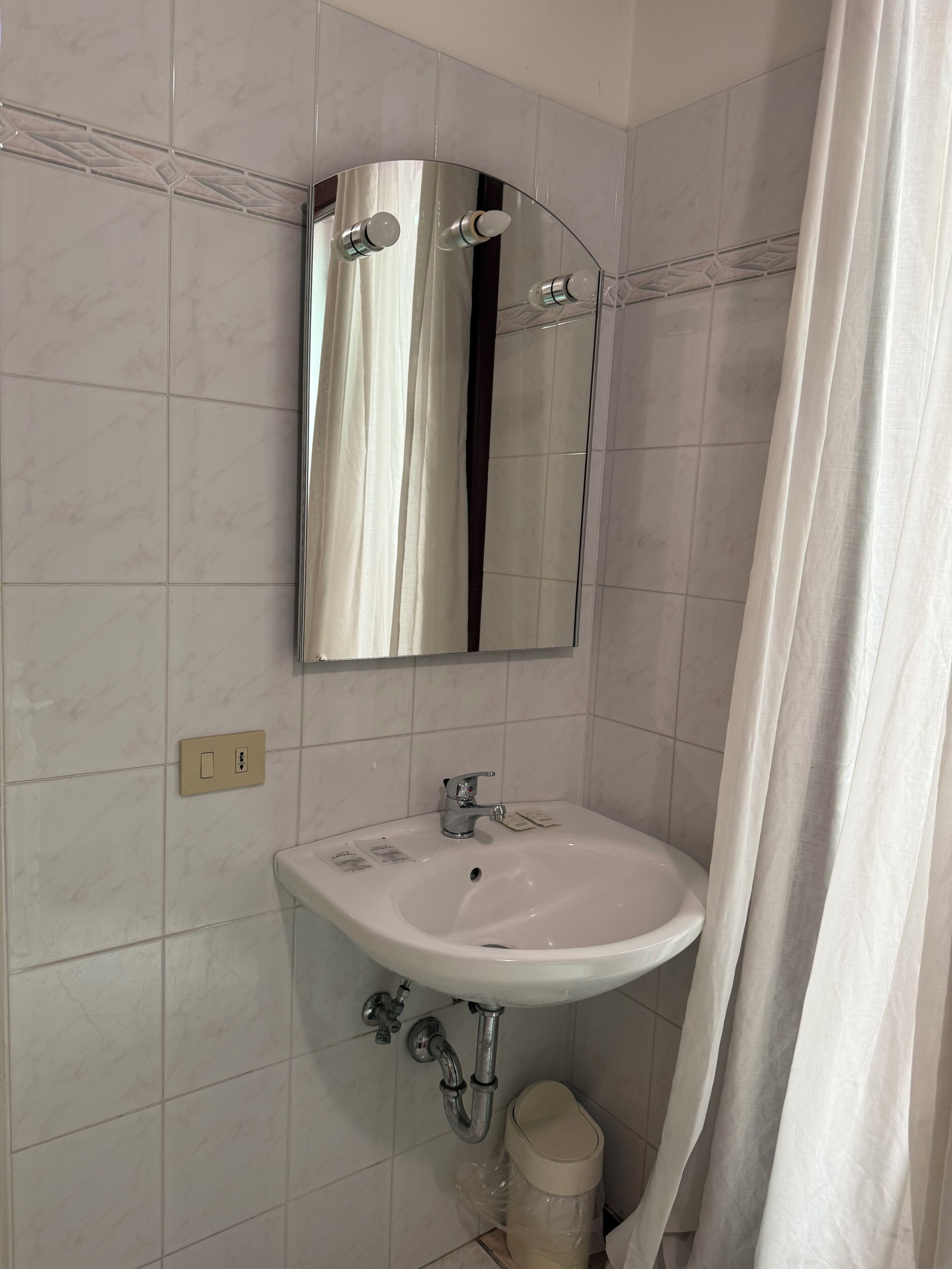 A bathroom with a white sink, a mirror, and a shower curtain.