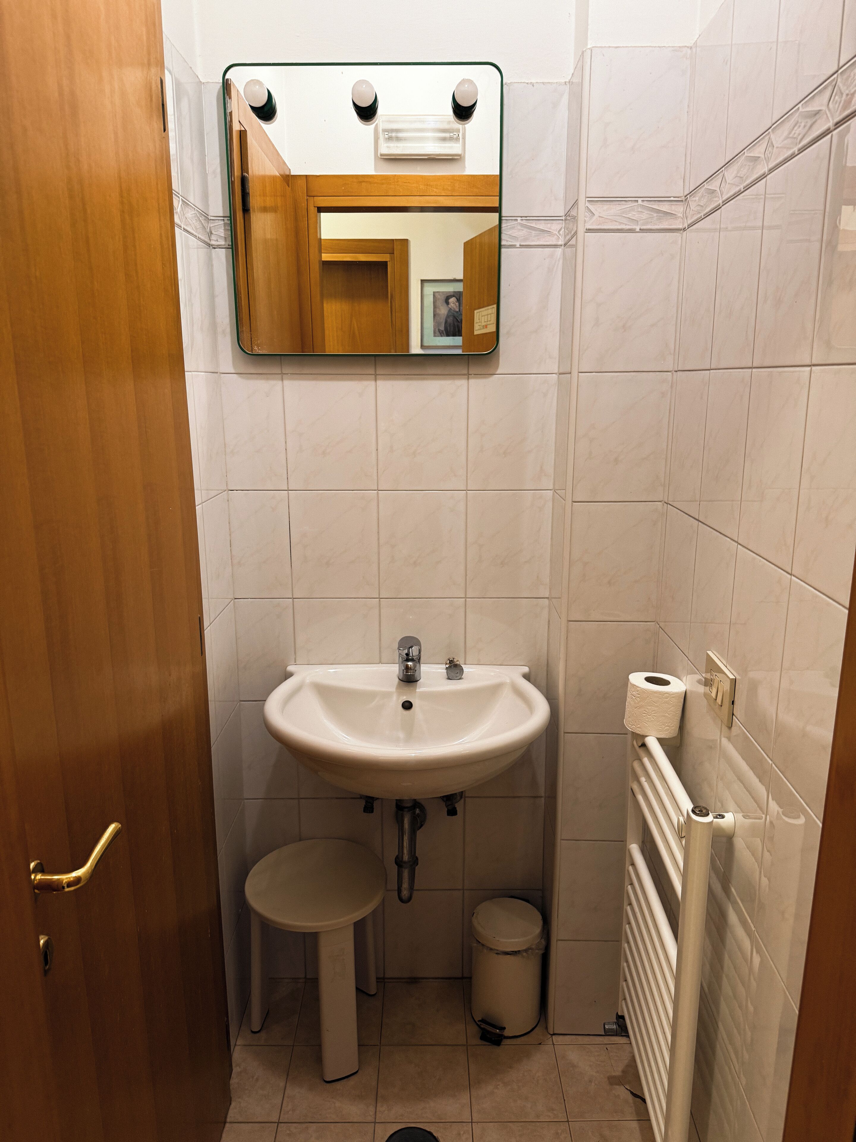 Ein Badezimmer mit Waschbecken, Spiegel, Toilette und Heizkörper.