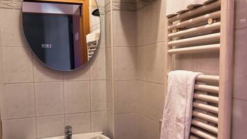Une salle de bain équipée d’un lavabo, d’un miroir, d’un porte-serviettes et d’une poubelle.