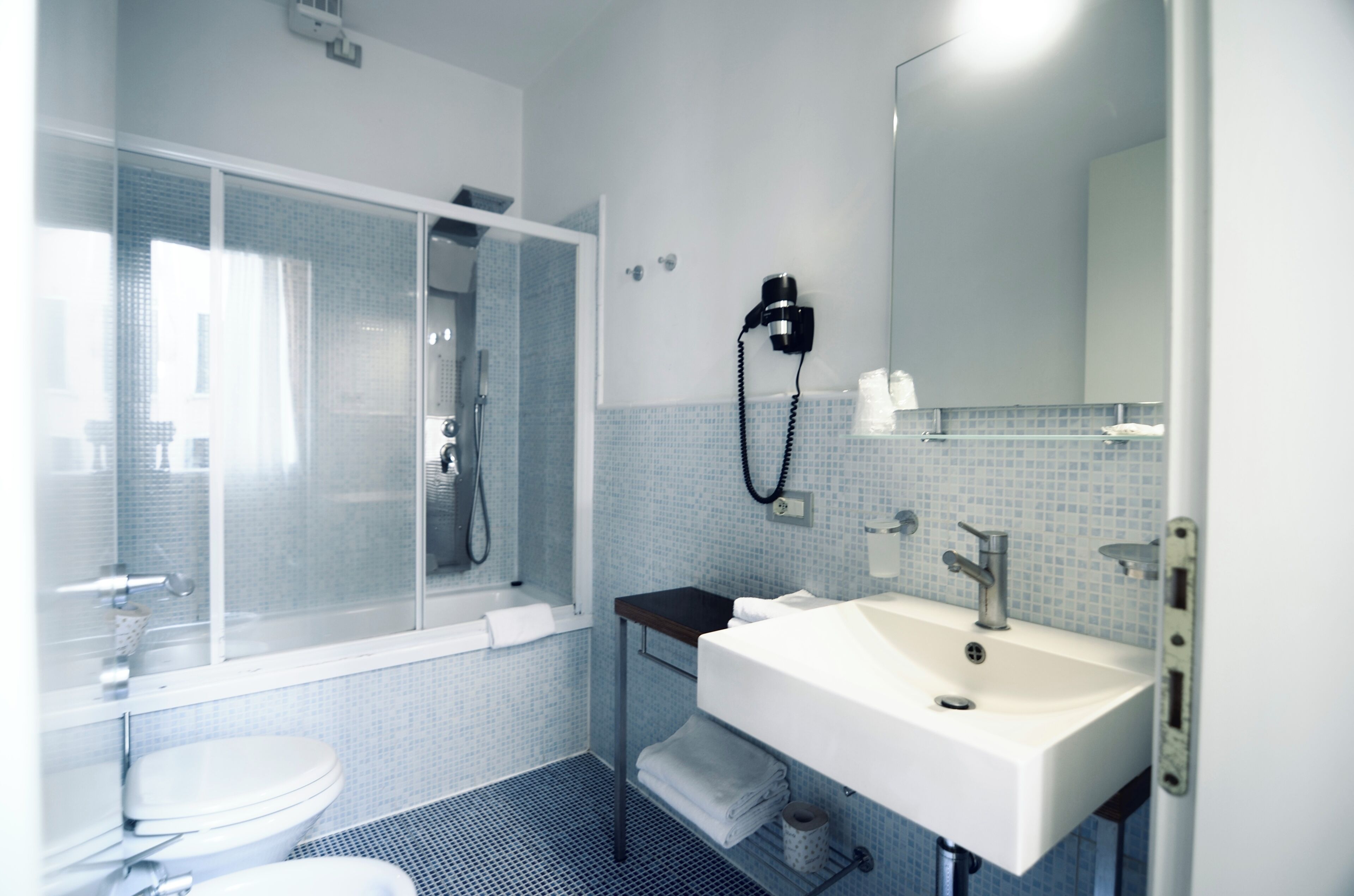 Ein Badezimmer mit Dusche, Toilette, Waschbecken und Spiegel.