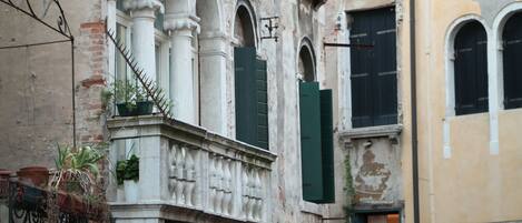 A historic building with a balcony, arched windows, and a brick facade.