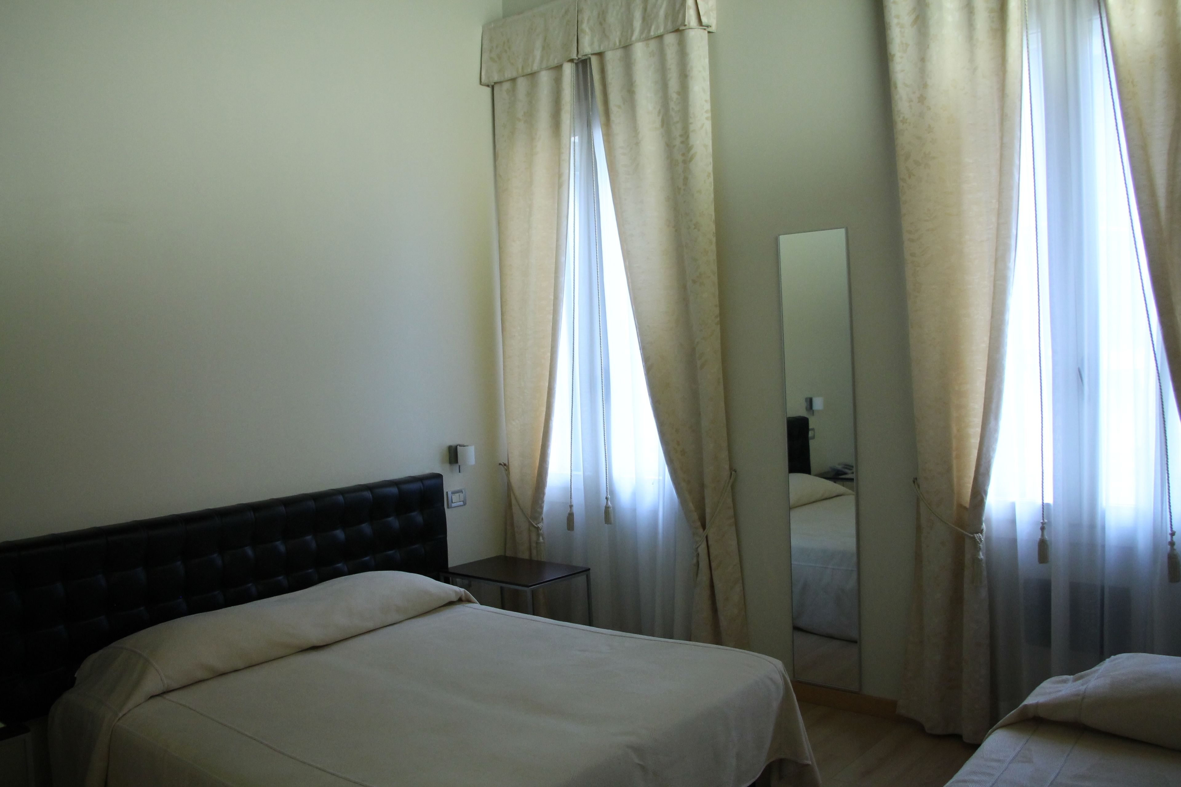 Een hotelkamer met een enkel bed, een tafeltje en een spiegel.