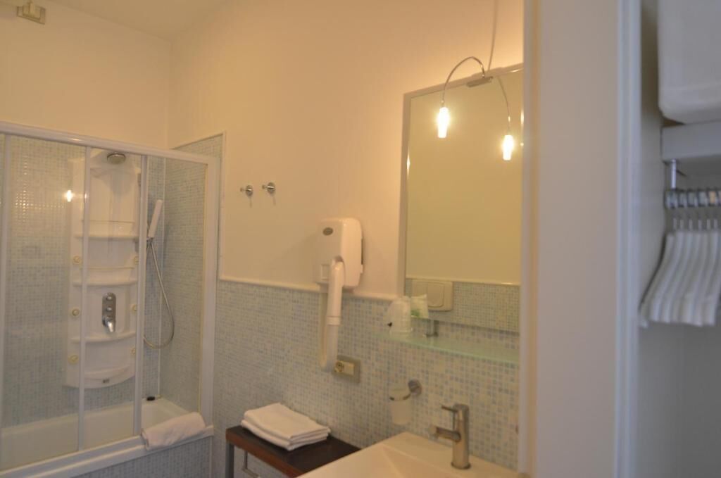 A bathroom with a glass-enclosed shower, a sink, a mirror, and a towel rack.