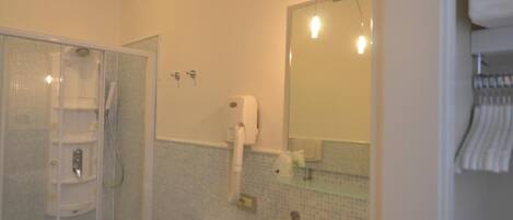 A bathroom with a glass-enclosed shower, a sink, a mirror, and a towel rack.