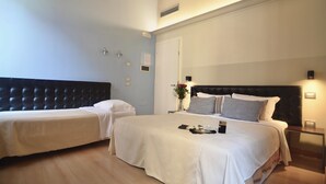 A hotel room with two beds, a wooden ceiling, a white wall, and a nightstand with a lamp. - Hotel Tiepolo (Venice)