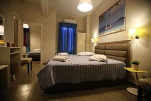 A bedroom with a large bed, a bedside table with a lamp, a wardrobe, and a painting on the wall. - Paradise Rooms (Syros)