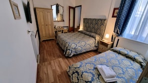 Une chambre avec deux lits, une armoire en bois, un bureau et un miroir.