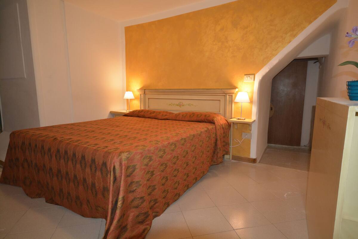 A hotel room with a bed, nightstands, and a staircase.