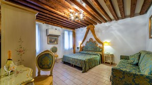 A bedroom with a four-poster bed, a sofa, a table with a bottle and glasses, and a chair. - Hotel Al Vagon (Venice)