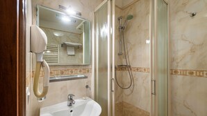 A bathroom with a white sink, a mirror, a hairdryer, and a glass-enclosed shower. - Hotel Al Vagon (Venice)