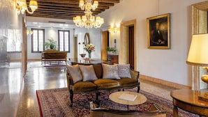 Un hall d’entrée spacieux avec un plafond haut, un lustre, un canapé, une table basse et une grande fenêtre.